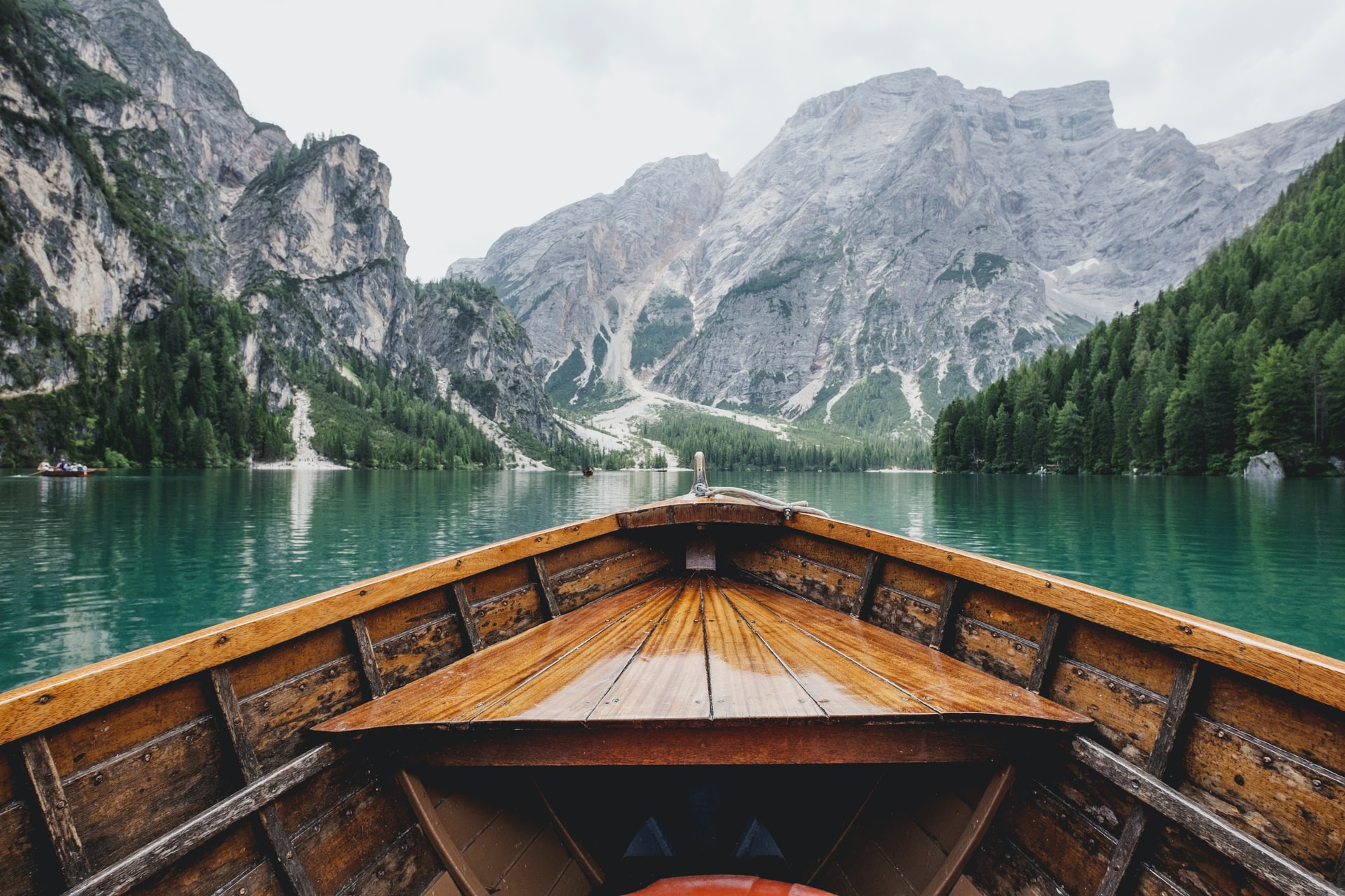 Brown wooden boat moving towards the mountain